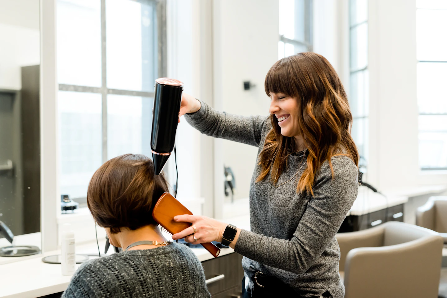 Hair stylist finishing a guest’s look in a bright studio
